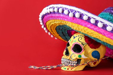 Meksika Ölüler Günü için boyanmış insan kafatası (El Dia de Muertos) ve renk arka planında sombrero