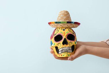 Meksika Ölüler Günü (El Dia de Muertos) ve aydınlık arka planda sombrero için boyanmış insan kafatasına sahip eller