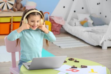 Laptop eğitimi almış küçük bir kız evde harfleri telaffuz ediyor.