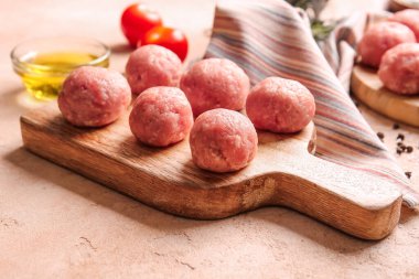 Hafif arka planda taze etten yapılmış çiğ pirzolaları olan ahşap tahta.