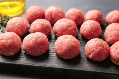 Koyu arka planda taze etten yapılmış çiğ pirzola ile ahşap tahta, yakın plan.