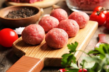 Tahta arka planda taze etten yapılmış çiğ pirzolalar, yakın plan.