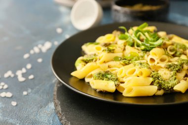 Renkli arka planda lezzetli makarna ve pesto soslu tabak, yakın plan.