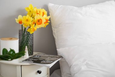 Narcissus çiçekli vazo komodinin yanında, odada.