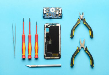Renk arkaplan üzerinde teknisyen araçları olan parçalanmış cep telefonu