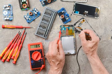 Erkek teknisyen Grunge arka planında hasarlı cep telefonunu tamir ediyor