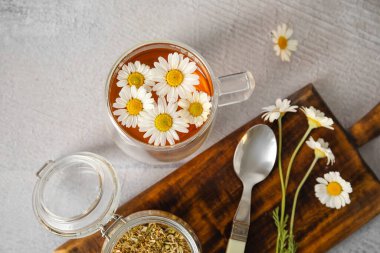 Bir fincan papatya çayı ve arkaplanda kurumuş çiçeklerle kompozisyon.