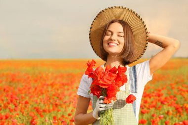 Tarlada bir buket haşhaş çiçeğiyle güzel bir kadın çiftçi