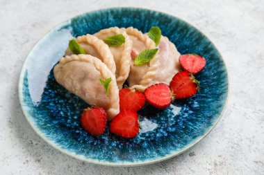Açık arkaplanda lezzetli çilekli börek tabağı.