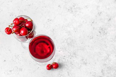 Bir kadeh şarap ve arka planda tatlı kiraz.