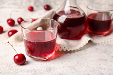 Hafif arka planda tatlı kiraz şarabı kadehleri ve sürahisi, yakın plan.