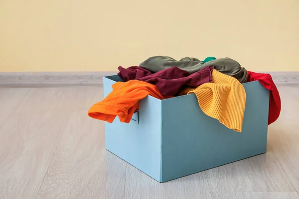 Wardrobe box with clothes near color wall