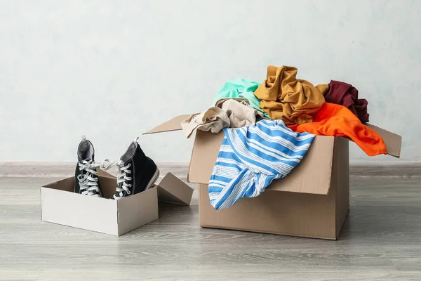 Wardrobe boxes with clothes and shoes near light wall