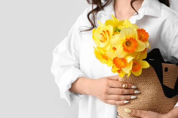 若いです女性とともに美しいです花束のナルシス花で袋の中に光の背景 — ストック写真