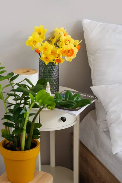 花瓶ともにナルシシズムの花のベッドサイドテーブルで部屋 — ストック写真