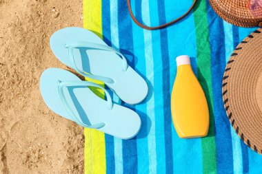 Havalı parmak arası terlikler ve kumdaki plaj aksesuarları, yakın plan.