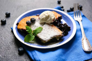 Koyu arkaplanda yabanmersinli tart ve dondurma parçaları, yakın plan.