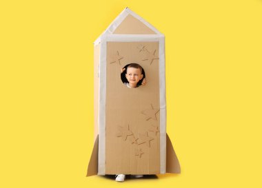 Renkli arka planda karton roketle oynayan sevimli küçük çocuk.