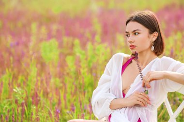 Çiçek açan alanda dinlenen güzel genç bir kadın.