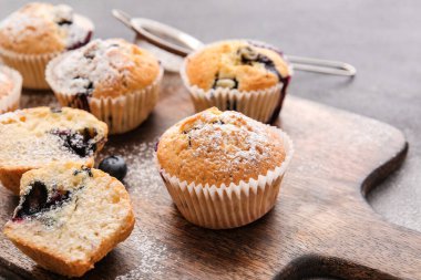 Koyu arkaplanda lezzetli yaban mersinli kekler olan tahta, yakın plan.