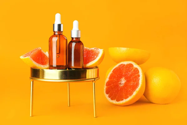 Composition with bottles of essential oil and grapefruits on color background