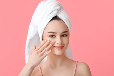 Güzel genç bir kadın yüzüne renkli arka planda masaj yapıyor.