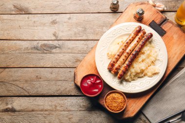 Lezzetli ızgara sosis, lahana turşusu ve ahşap arka planda soslar.