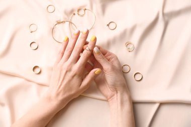 Kumaş arka planında güzel manikürlü ve aksesuarlı kadın elleri.