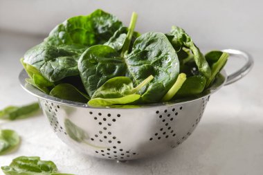 Hafif arka planda taze ıspanak yapraklı Colander, yakın plan.