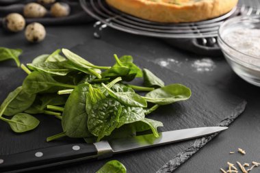 Koyu arkaplanda taze ıspanak ve bıçak, yakın plan.