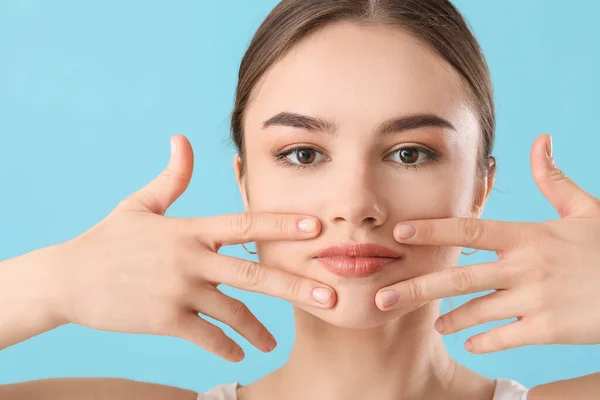 Hermosa Joven Masajeando Cara Sobre Fondo Color —  Fotos de Stock