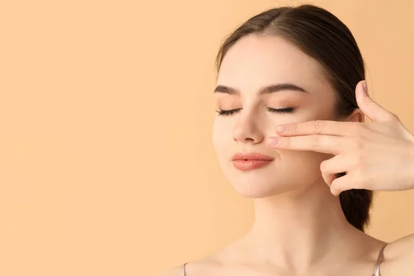 Hermosa Joven Masajeando Cara Sobre Fondo Color — Foto de Stock