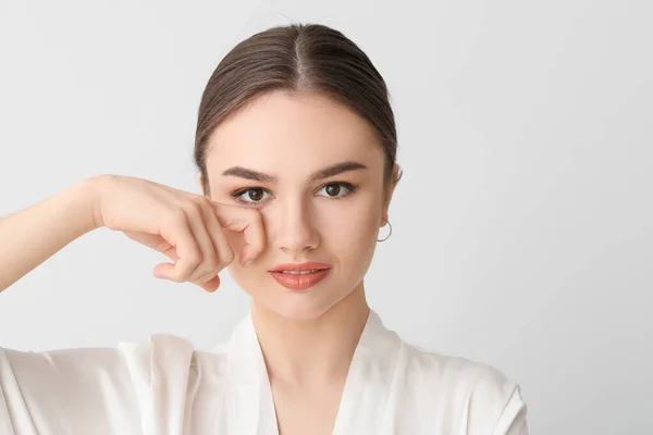 Hermosa Joven Masajeando Cara Sobre Fondo Claro — Foto de Stock