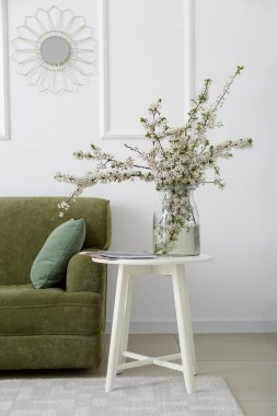 Oturma odasının içinde çiçek açan dalları olan vazo.