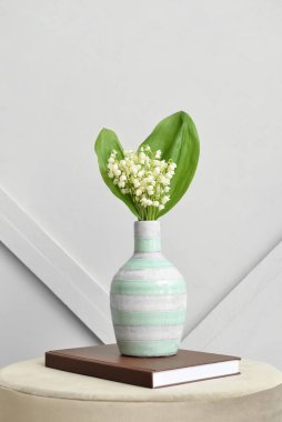 Işık duvarının yanındaki masada, vadideki güzel çiçekli vazo.