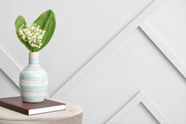 Işık duvarının yanındaki masada, vadideki güzel çiçekli vazo.