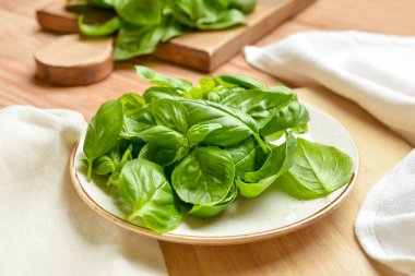 Ahşap arka planda taze fesleğen yapraklı tabak, yakın plan.