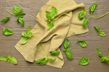 Taze fesleğen yaprakları ve ahşap arkaplanda peçete.