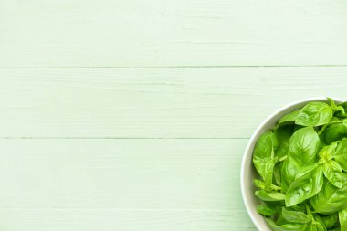 Renkli ahşap arka planda taze fesleğen yapraklı kase