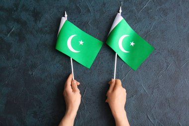 Koyu arkaplanda Pakistan bayrakları olan kadın eller