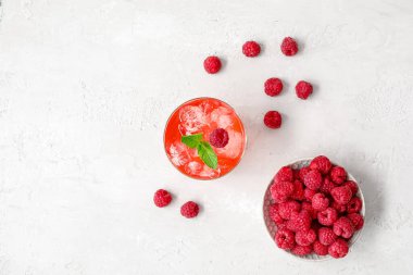 Bir bardak lezzetli limonata ve arka planda ahududulu kase.