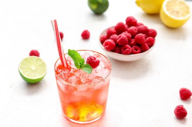 Bir bardak lezzetli limonata ve arka planda ahududulu kase.