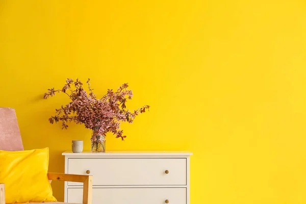 Renkli Duvarın Yanındaki Çekmecelerin Üzerinde Çiçek Açan Dallar Olan Vazo — Stok fotoğraf