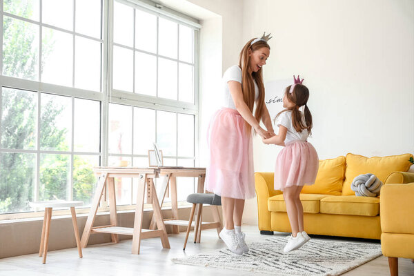 Молодая женщина и ее маленькая дочь танцуют дома