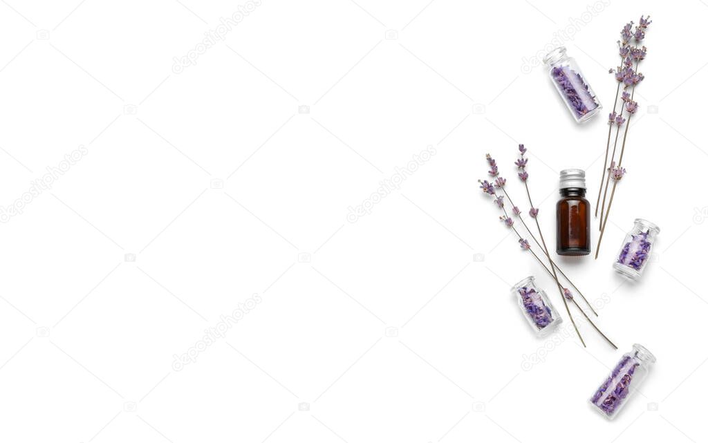Bottle of essential oil and lavender flowers on white background