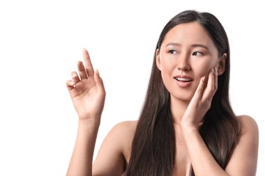 Güzel genç bir kadın beyaz arka plandaki bir şeyi işaret ediyor.