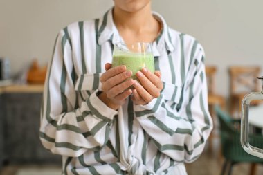 Genç Afro-Amerikalı kadın mutfakta taze meyve suyu içiyor.