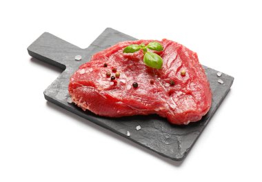 Board with raw beef meat and spices on white background