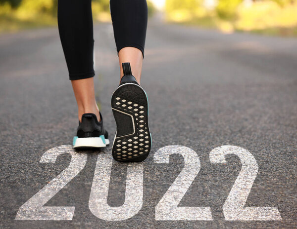 Sporty young woman on road. Concept of new years goals