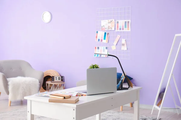 Stylish workplace of graphic designer with laptop in office